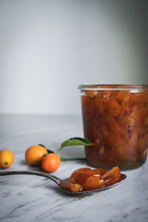 A spoon resting on counter filled with candied kumquats