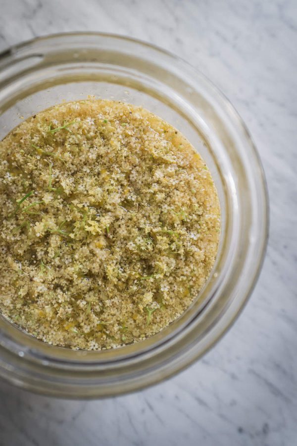 looking into a glass jar, filled with elderflowers infusing for cordial