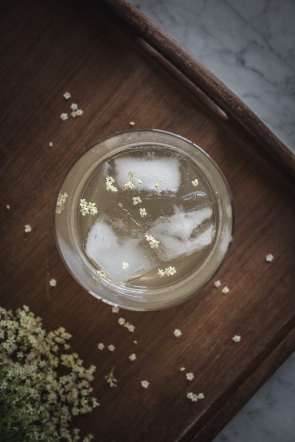 looking down into glass filled with elderflower cordial and ice cubes