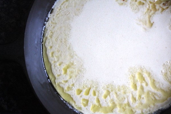 Dutch baby batter in a cast iron pan, floating in a sea of butter