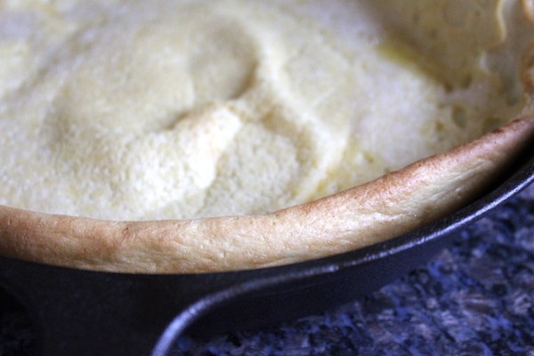 Edge of a homemade dutch baby pancake in a cast iron pan