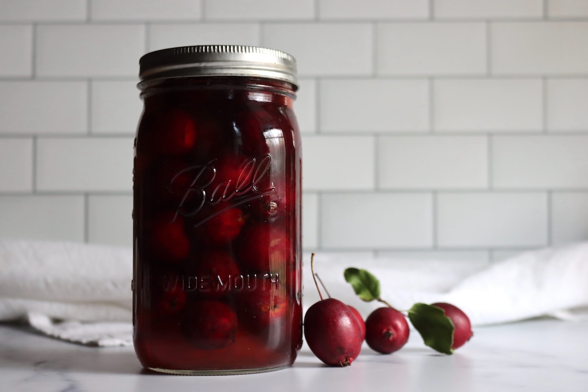 Jar of spiced pickled crabapples with the stems left on